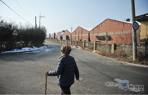 과거 예산군 근대화의 상징이었던 옛 충남방적주식회사 예산공장 담벼락을 따라 한 어르신이 지팡이를 짚고 지나가고 있다. ⓒ 무한정보신문